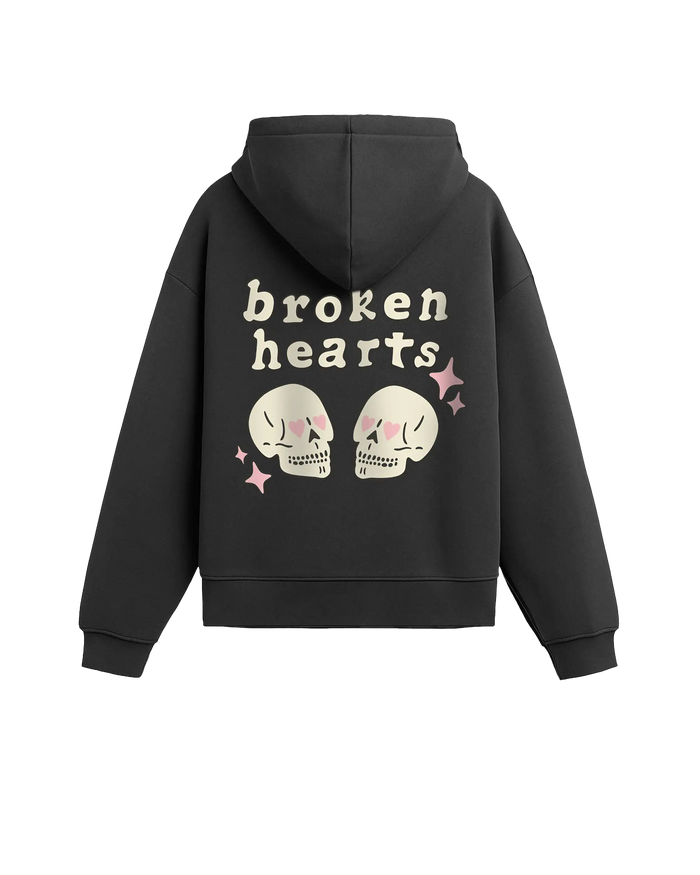 #füme renk hoodie arka görünüm; sırt baskısında “broken hearts” yazısı, pembe kalp gözlü iki krem kafatası illüstrasyonu ve pembe parıltı ikonları.