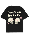 #siyah oversize boxy fit Southline tişört; arka baskıda “broken hearts” yazısı, kalp gözlü iki kafatası illüstrasyonu ve pembe yıldız detayları bulunan 280 GSM heavy-weight pamuk streetwear t-shirt.
